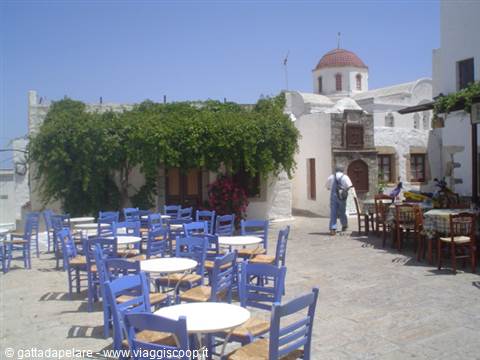 Small square with blue tables and red-domed church in the Cyclades