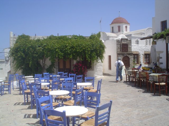 Small square with blue tables and red-domed church in the Cyclades
