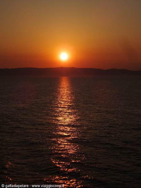 Low sun reflecting gold on the sea before dark hills