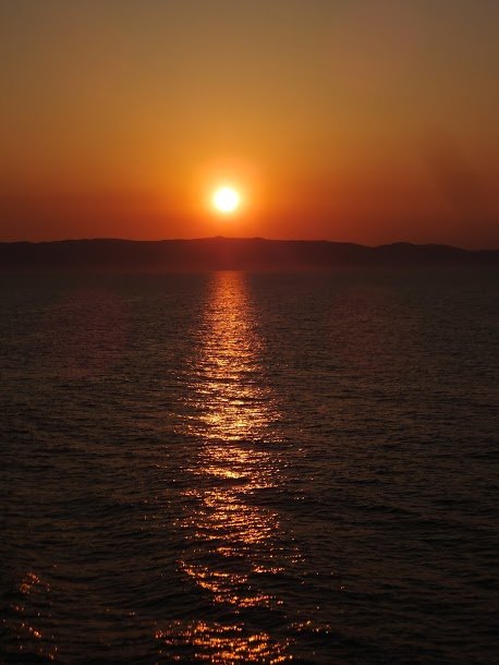 Low sun reflecting gold on the sea before dark hills