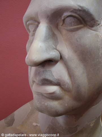 Marble face of ancient Roman statue against red background