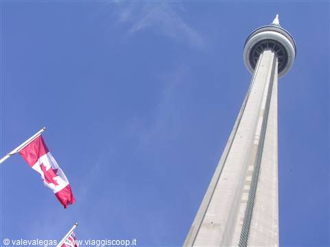 The CN Tower in Toronto against blue sky with the Canadian flag
