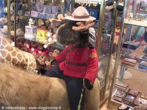 Moose plush wearing red Mountie uniform and hat riding a toy horse in shop