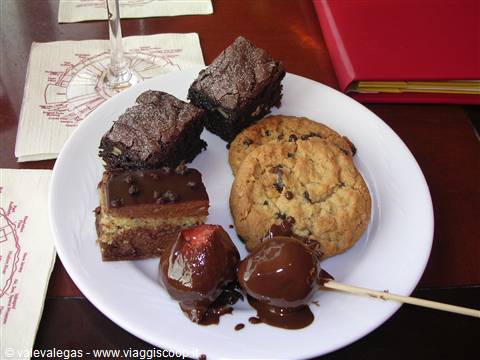 White plate with brownies, cookie, chocolate cake and chocolate-covered strawberries on table