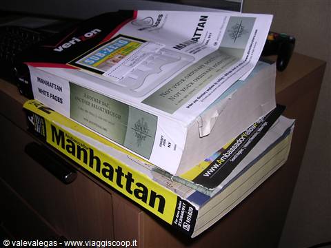 Manhattan phone directories and Yellow Pages stacked on a wooden cabinet