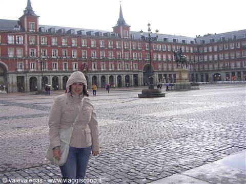 Smiling tourist at Madrid's Plaza Mayor, red buildings, gray sky