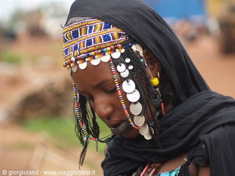 Woman wearing beaded headdress with silver discs, pensive expression
