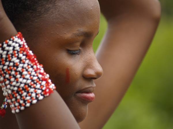 Young woman wearing red, white and black beaded bracelets in natural light