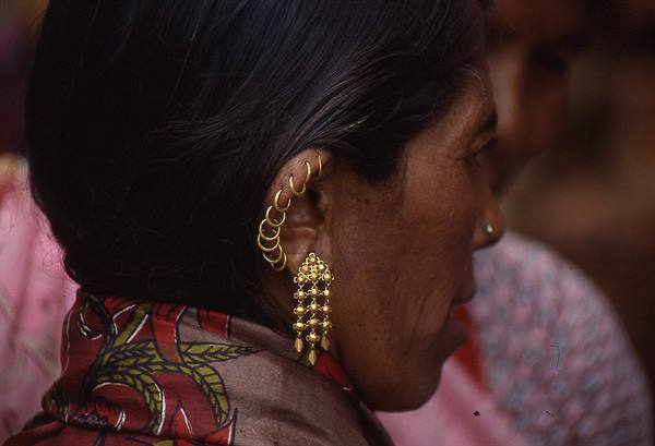 Woman with gold rings along her ear and dangling earring, nose stud