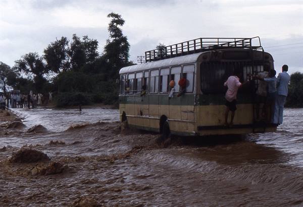 Bus stuck in flooded mud, passengers boarding through the rear door