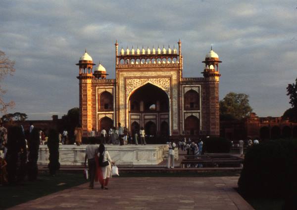 Marble and sandstone gateway of the Taj Mahal, visitors in golden light