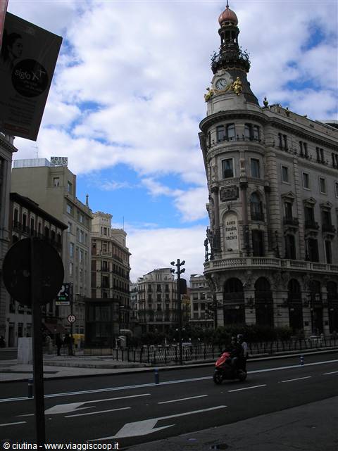 A scooter rides past the clock-topped building on Madrid's Gran Vía
