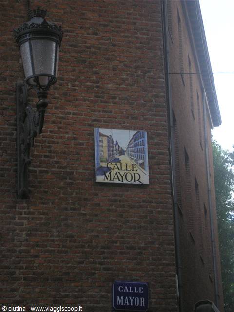 Ceramic Calle Mayor street sign on brick wall, black iron lantern