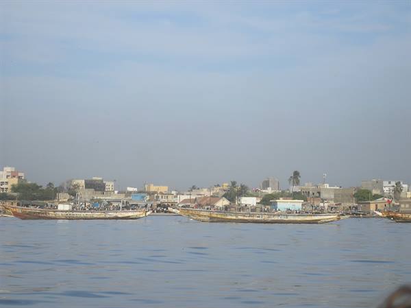Wooden fishing boats moored in front of low city buildings