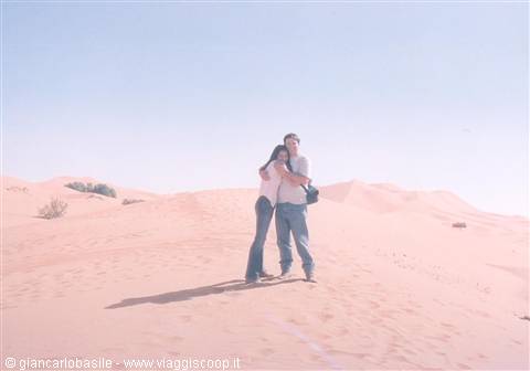 Couple embracing on a red sand dune in the desert