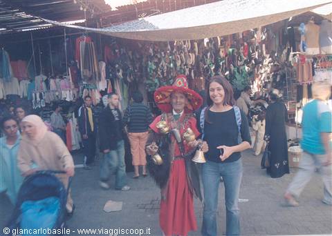 Tourist next to a red-costumed water seller in Marrakech souk