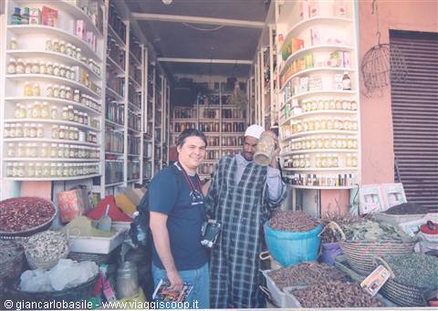Tourist with camera beside vendor inside Marrakech spice souk shop