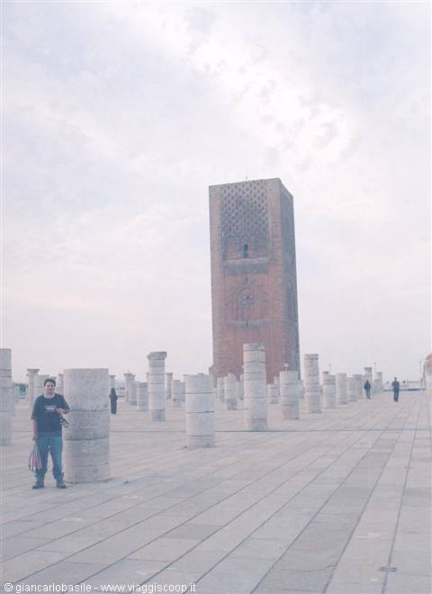 Tourist among Hassan Tower columns, pale stone under cloudy sky