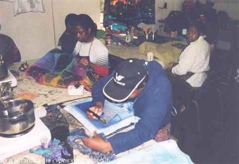 Artisans painting colorful batik fabrics in a Zambian workshop