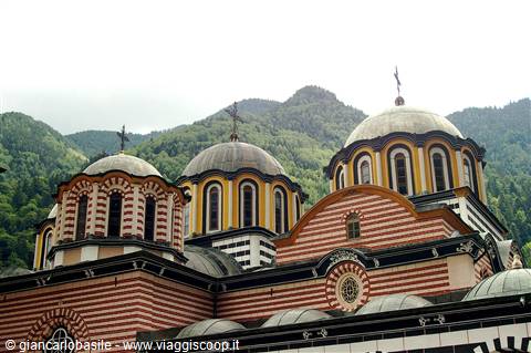 Rila Monastery: striped domes and crosses above forested mountains