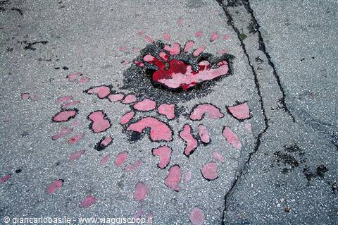 Pink paint splatters scattered on cracked grey asphalt