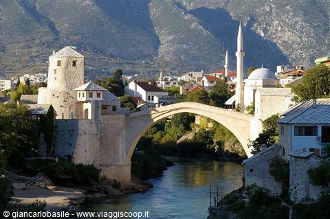 Mostar's Old Bridge arching over the Neretva river, with minaret and stone tower