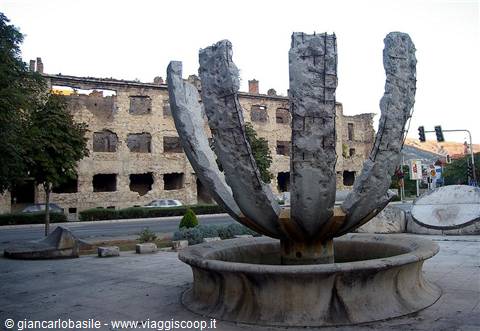 Stone petal fountain in front of Mostar's bombed building