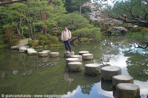 Tourist crossing stone stepping pads in the pond, Kenrokuen Garden, Kanazawa