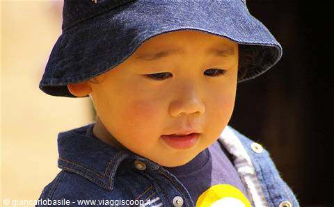 Toddler in denim bucket hat looks pensive, warm sunlight on his face