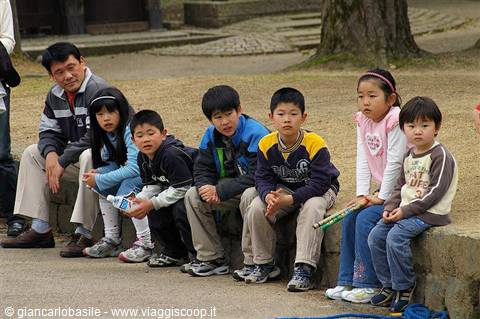 Children sitting on a low stone wall in a park
