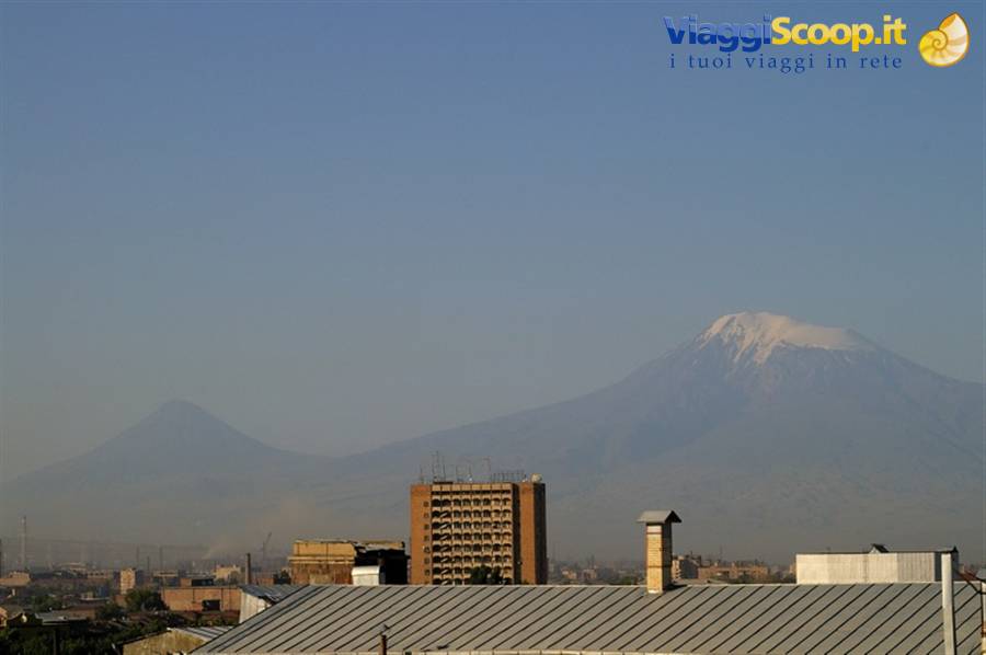 Snow-capped Mount Ararat rises above the hazy city rooftops