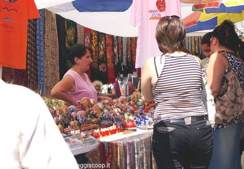 Shopper browsing t-shirts and souvenirs at an open-air market stall