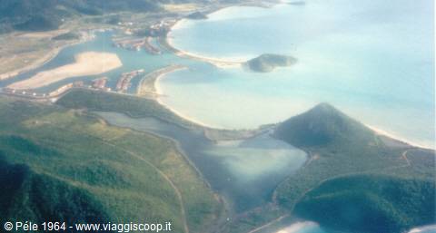 Tropical bay with white sand beach, green hills and turquoise waters from above