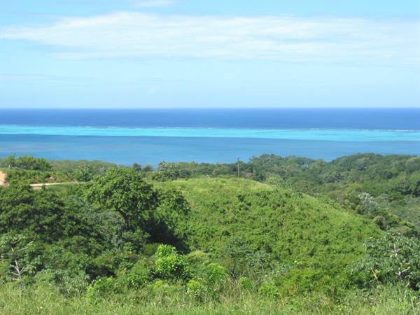 Green hills in front of turquoise reef under blue sky