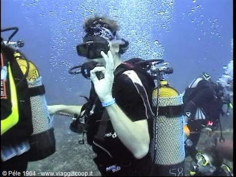 Scuba diver with tank and regulator making the ok sign among bubbles