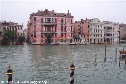 Pink palaces facing the Grand Canal in Venice, striped mooring poles under grey light