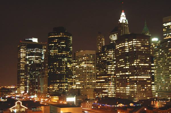 Manhattan skyscrapers lit up at night, yellow windows glowing against black sky