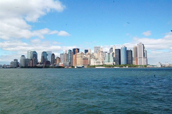 Manhattan skyline seen from the ferry, glass skyscrapers under cloudy sky