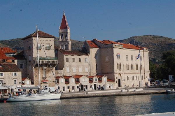 Trogir waterfront with cathedral bell tower and sailboat in the harbor