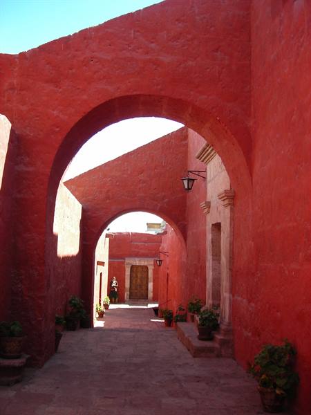 Deep red arches and potted plants inside Santa Catalina monastery, Arequipa