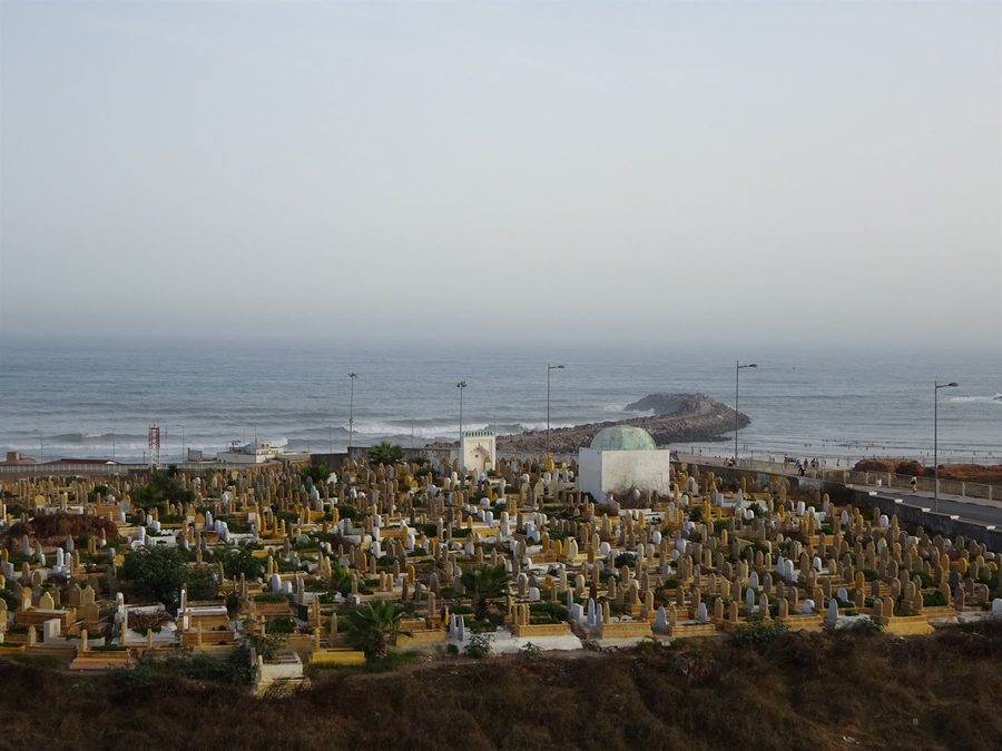 Cimitero con tombe bianche e cupola verde davanti all'oceano, Rabat