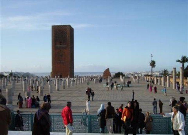 Visitors across the wide stone plaza of the Hassan Tower, unfinished columns and blue sky in Rabat