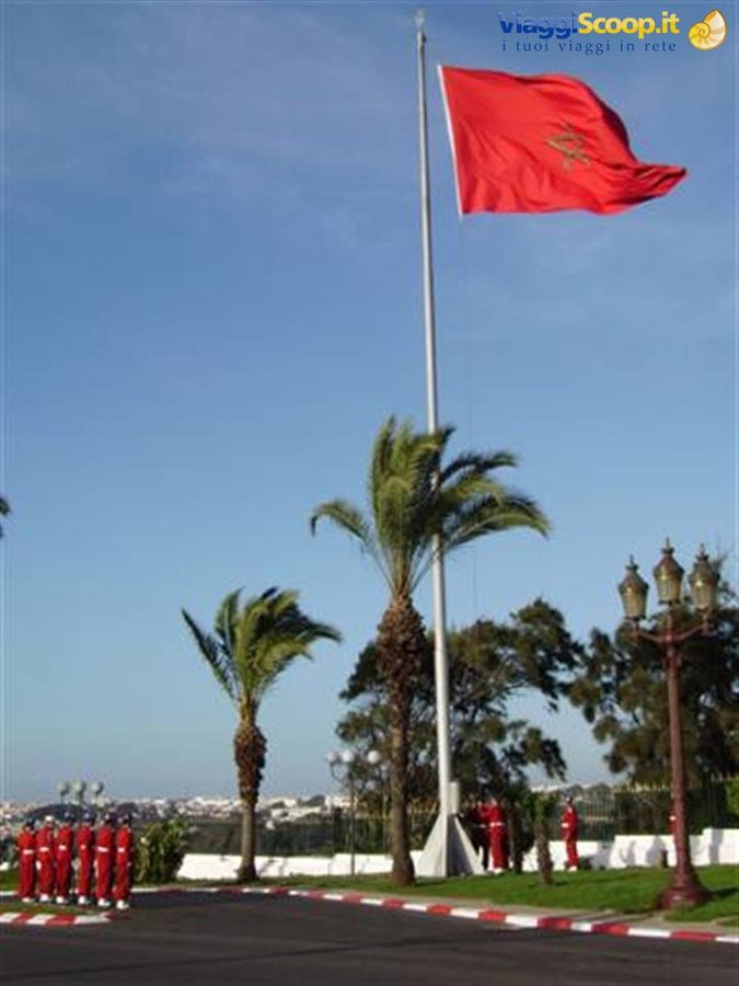 Red-uniformed royal guard beneath Morocco's flag outside the Royal Palace in Rabat