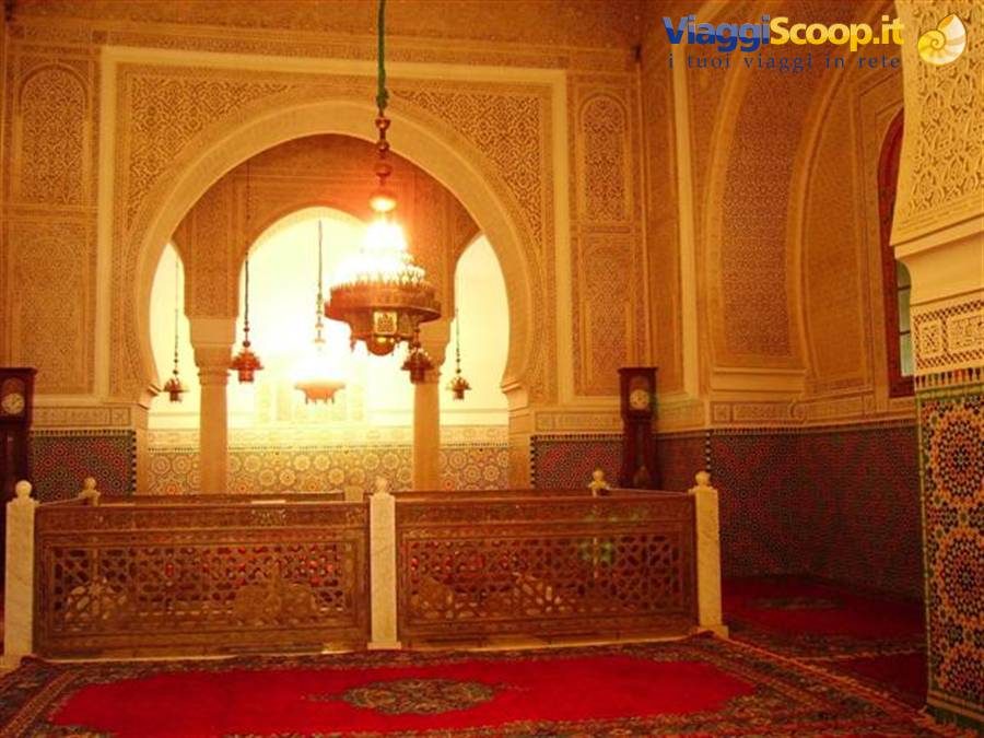 Meknes mausoleum interior: glowing chandeliers, carved stucco, zellige tiles and wooden screens