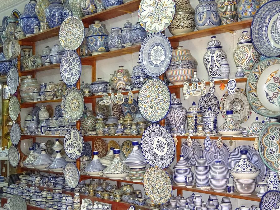 Blue and white ceramic plates and tajines displayed on shop shelves, Fes