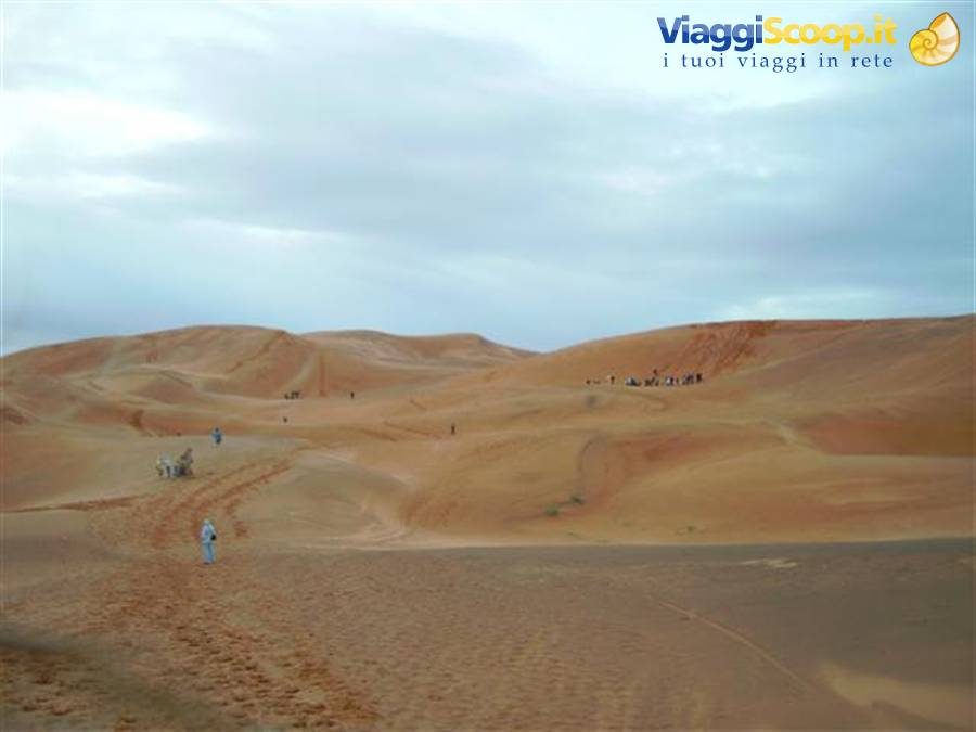 Tourists walking on the sand dunes of Erg Chebbi, Merzouga, under cloudy sky