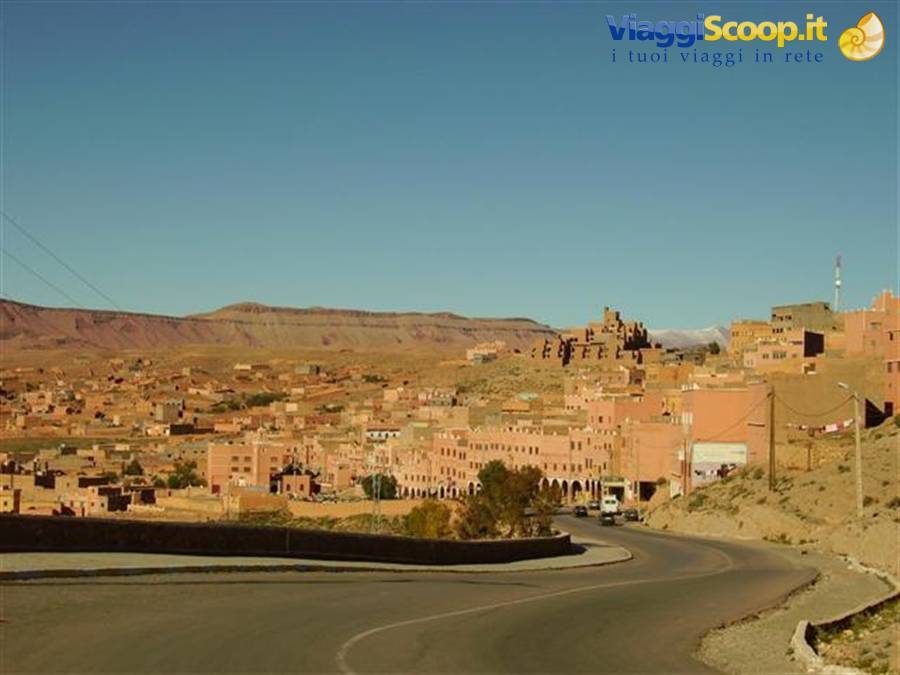 Ouarzazate town, red earthen buildings among mountains under blue sky