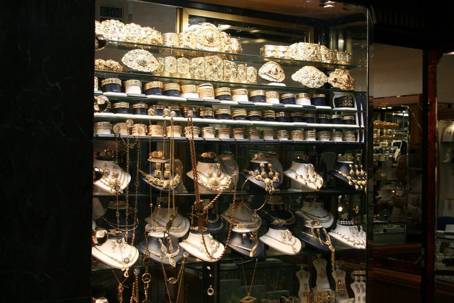 Jewelry shop window displaying golden necklaces and bracelets under warm light