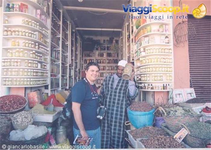 Tourist with camera beside vendor inside Marrakech spice souk shop